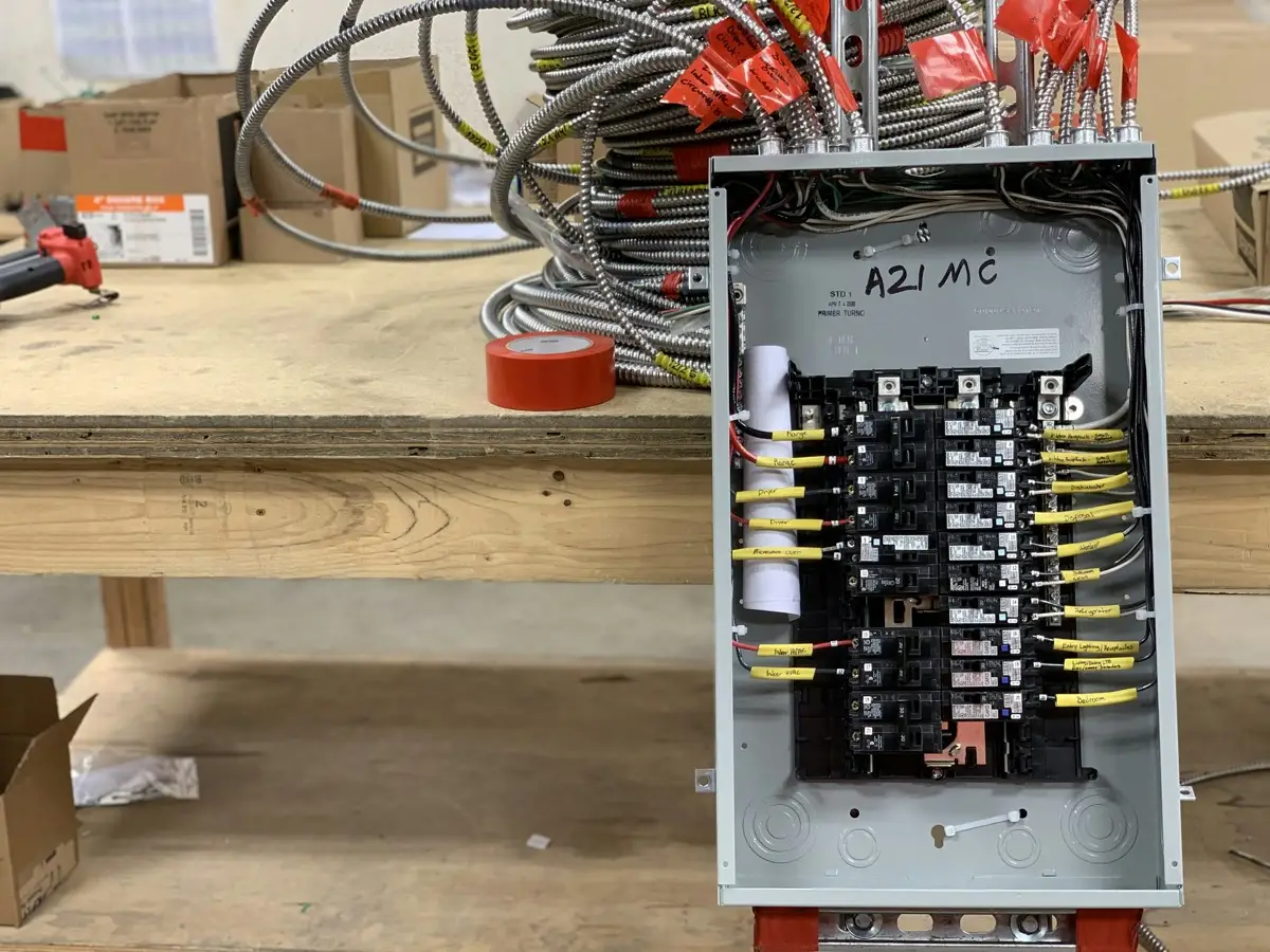 Photo of an open residential breaker panel with plug-in breakers and a handwritten yellow label on each circuit, such as range, dryer, dishwasher and kitchen receptacles