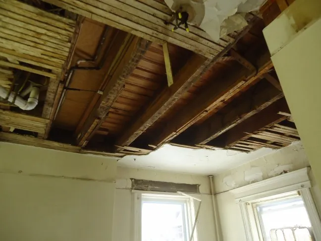 Old kitchen ceiling opened up, with plaster and wood lath partly pulled down between the joists